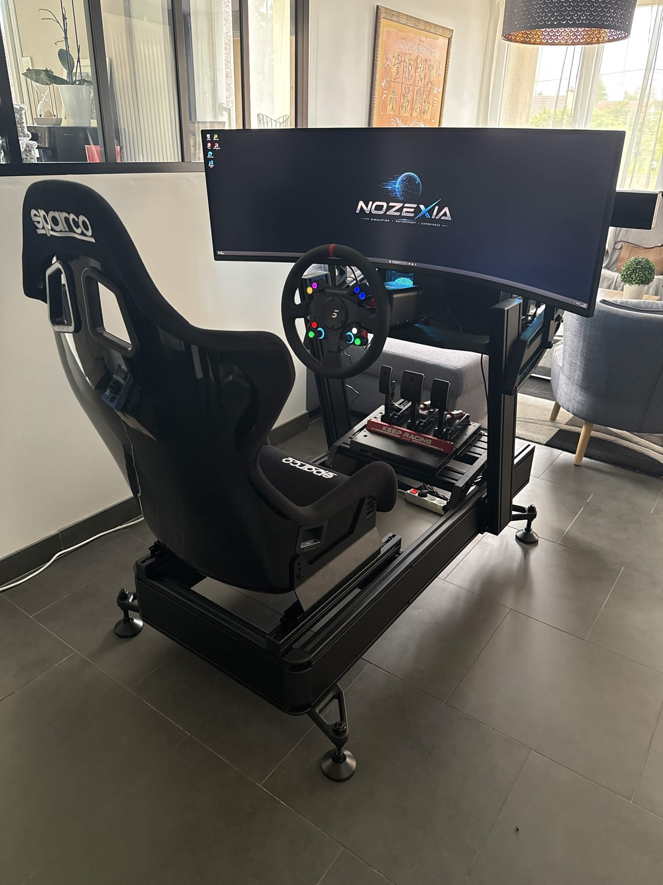 Setup NOZEXIA avec châssis simulateur, siège baquet, volant et écran ultralarge en cours de préparation.